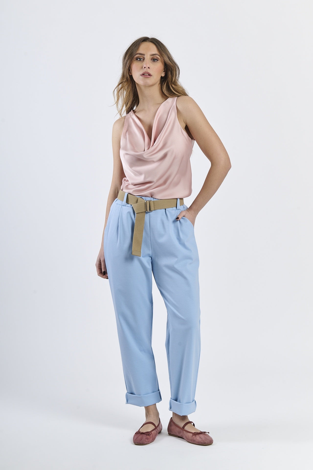 Outfit con top satinato rosa e pantaloni azzurri, cinghia in tonalità neutra